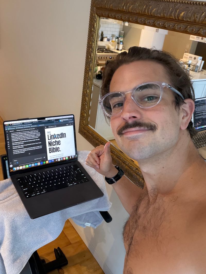 Matt Lakajev on the Concept2 bike with a laptop open, training for HYROX while running the business